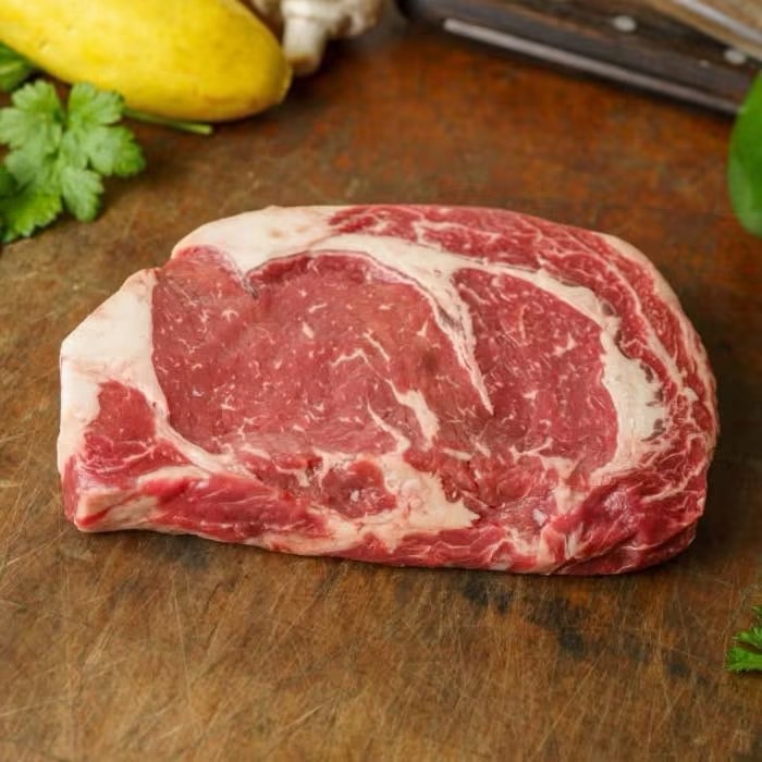 Marbled ribeye steak on a butcher block